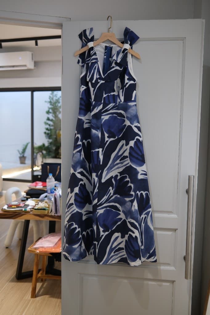 Blue and white abstract floral pattern dress with V-neck and bow straps on a hanger