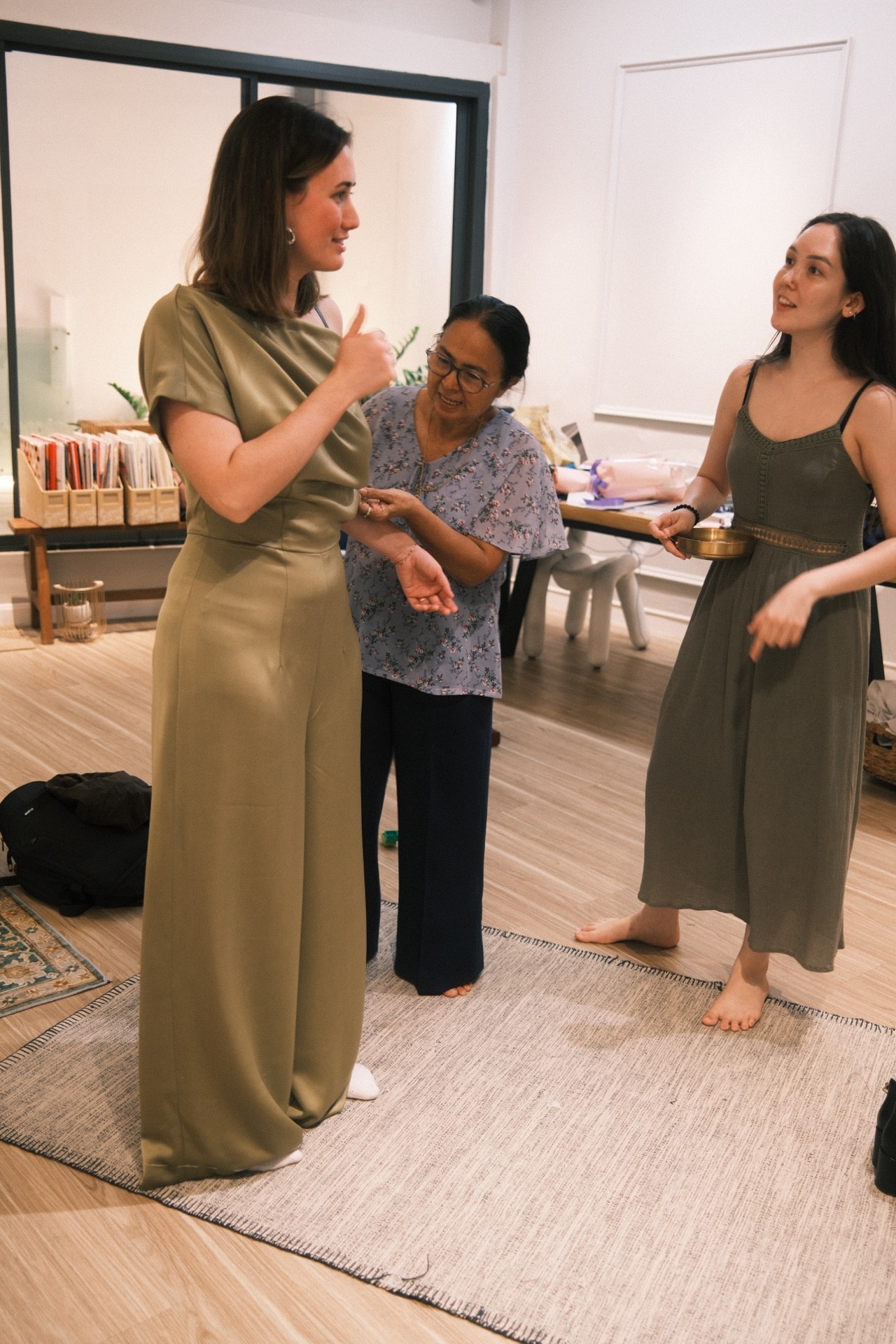 Customer in an olive jumpsuit laughing with a LALEDA tailor during a fitting